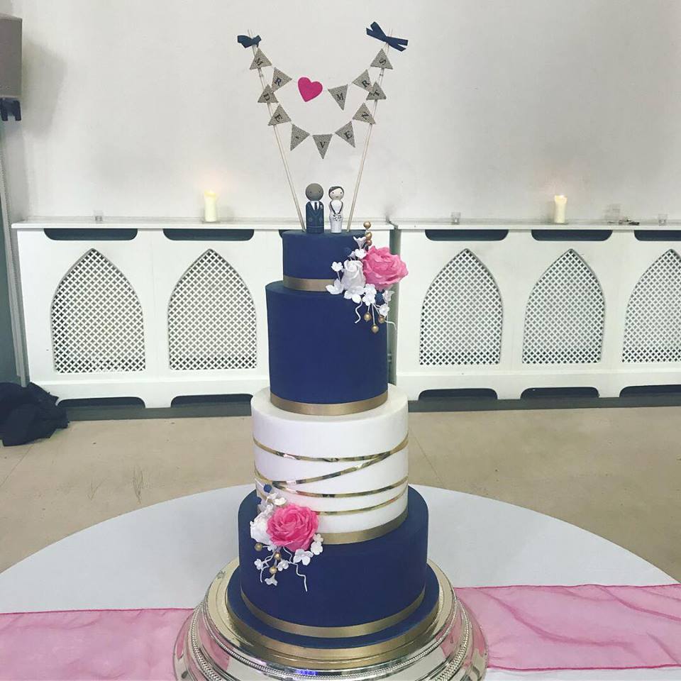 navy white and gold 3 tier wedding cake with beautiful fuchsia pink sugar roses and white blossom flowers