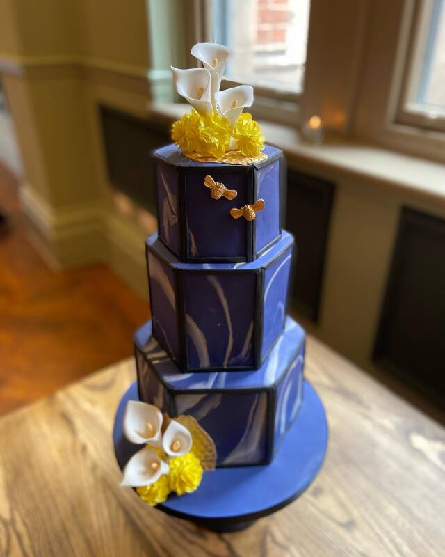 modern navy blue and black marble hexagon 3 tier wedding cake with beautiful handmade white sugar calla lillies and yellow carnations