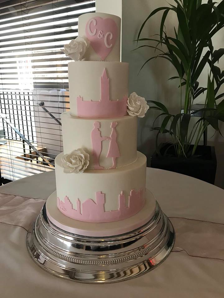 pink and white manchester skyline silhouette 3 tier wedding cake with handmade white sugar roses
