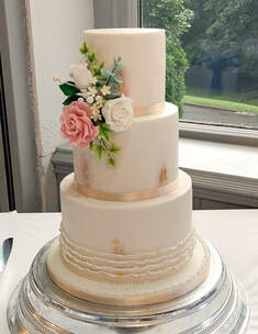 3 tier wedding cake with ruffles and sugar flowers and gold leaf detail
