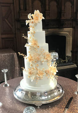 5 tier white wedding cake with ivory sugar orchids, calla lillies and foliage