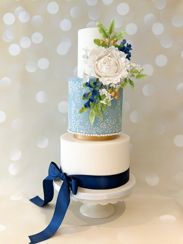 3 tier blue, white and gold wedding cake with white sugar peony, blueberries and green foliage 
