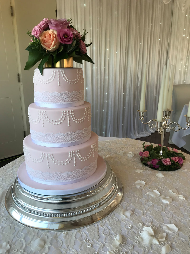 elegant 3 tier dusky pink wedding cake with beautiful lace and piped swags decoration